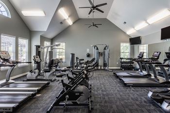 A gym with cardio machines and a ceiling fan